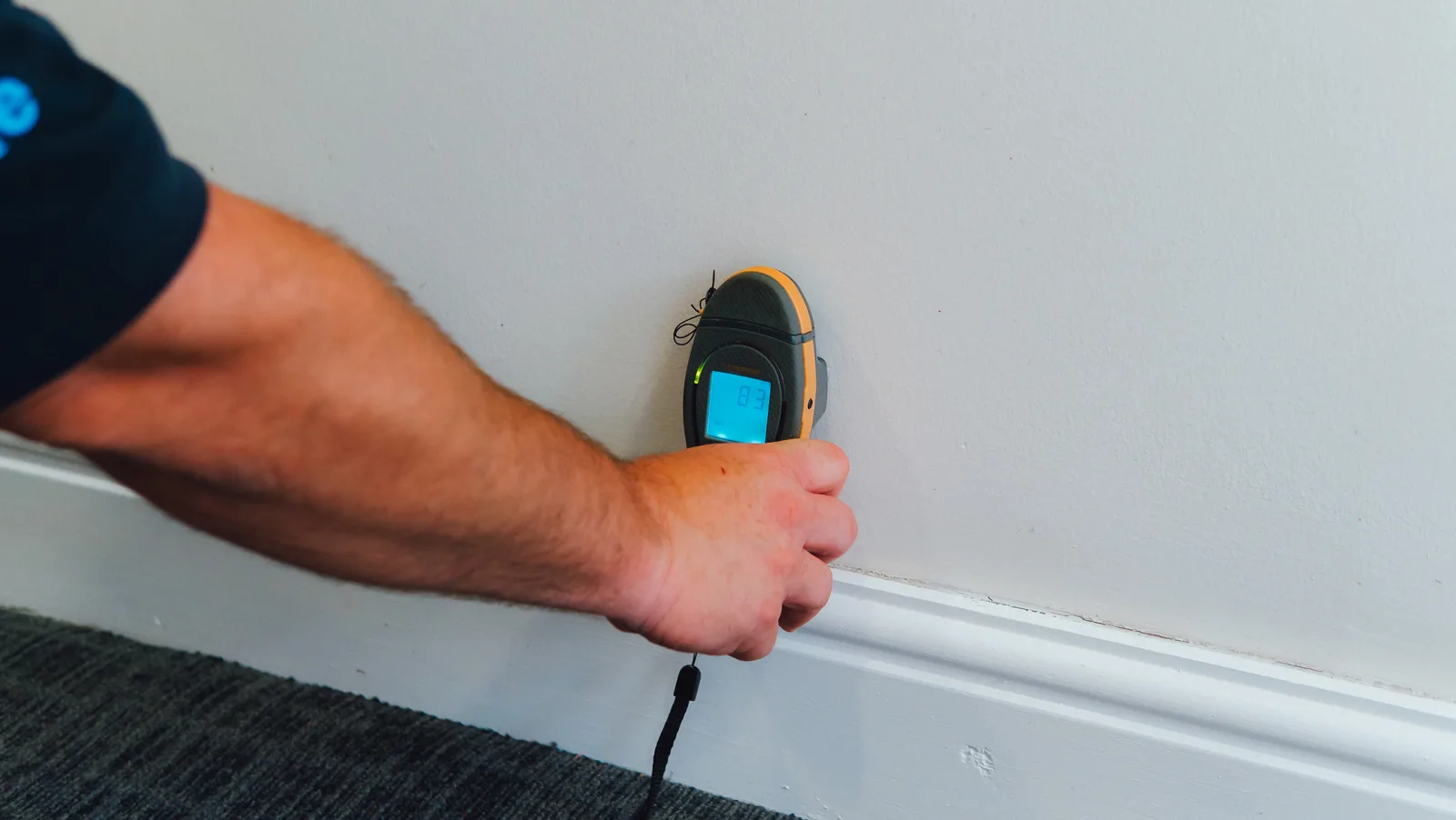 Engineer taking a moisture meter reading on an internal wall